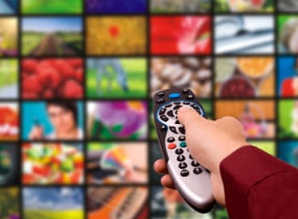 TV Advertising with Cable Commercials Works Shown By Viewer Clicking Remote Toward Busy TV Screen